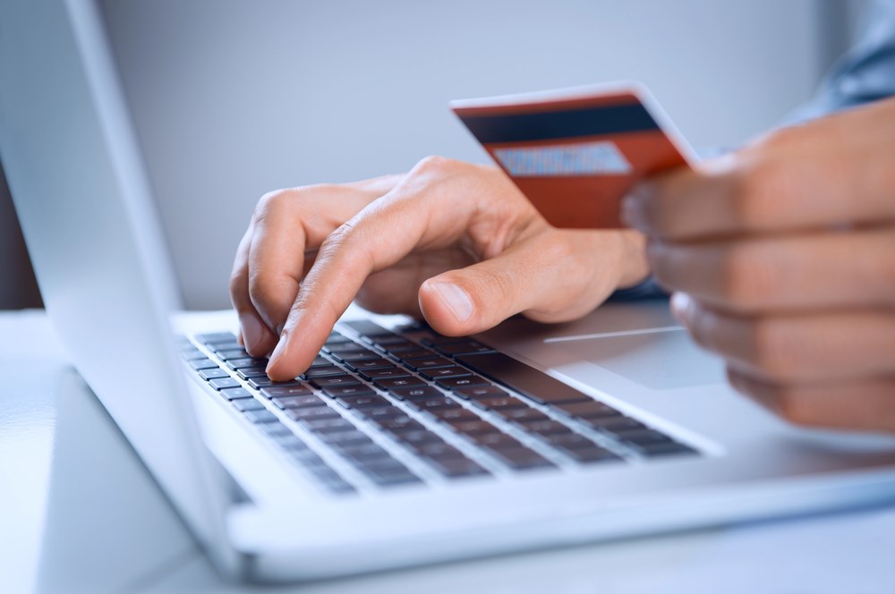 Cross-Border Transactions Image of a man making an online payment with a credit card, featuring 411 Corporate Law and highlighting cross-border transactions, ensuring it aligns with the page's context on international business dealings and financial regulations.